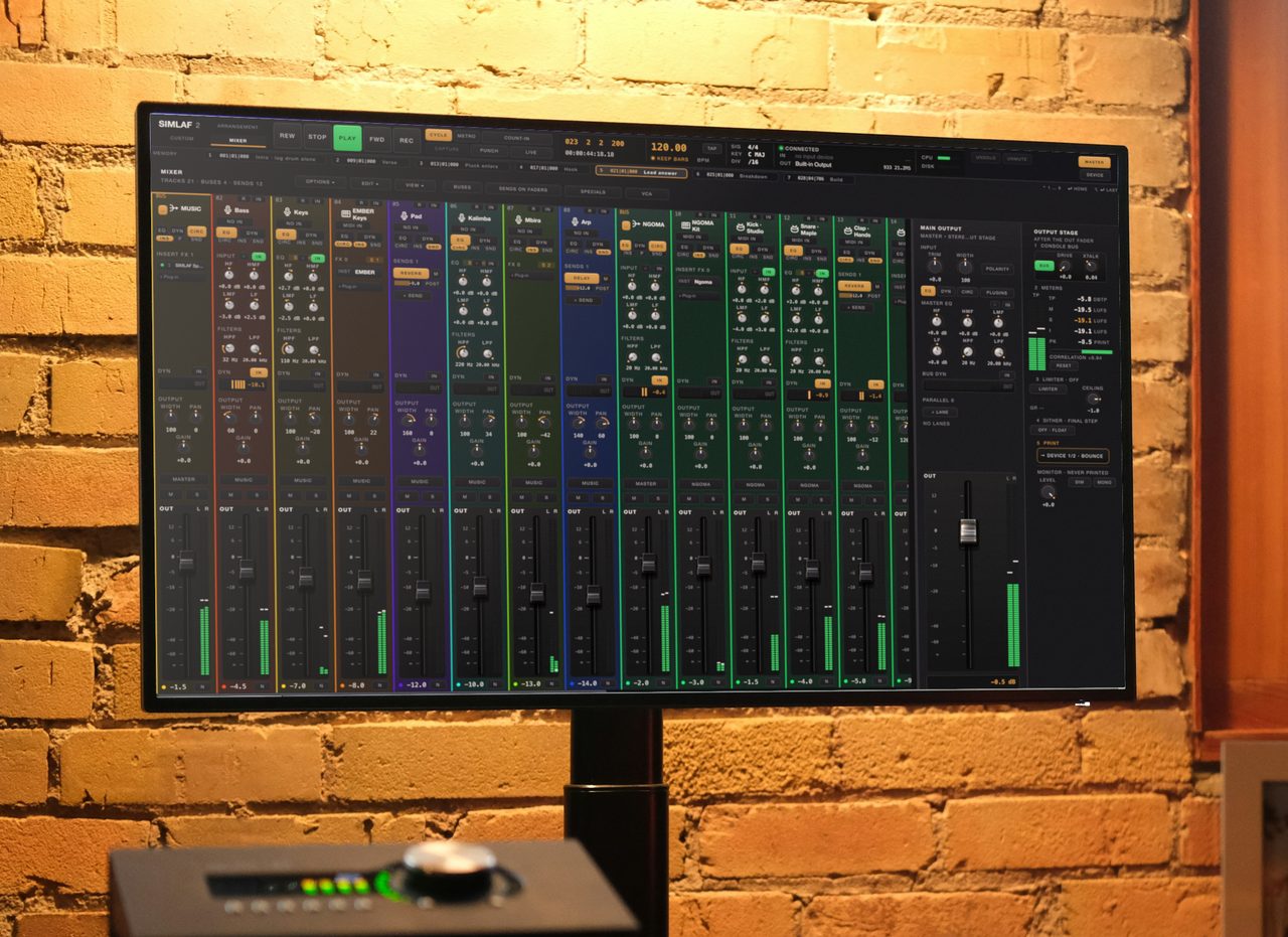 The SIMLAF 2 mixer on a studio monitor against a brick wall in late daylight, every channel set up differently, with a monitor speaker by the window