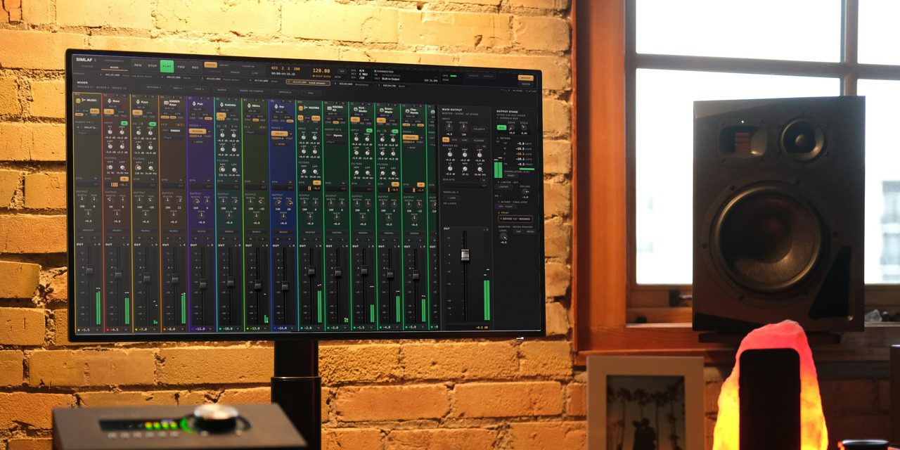 The SIMLAF 2 mixer on a studio monitor against a brick wall in late daylight, every channel set up differently, with a monitor speaker by the window